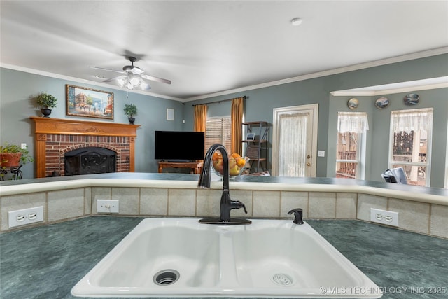 kitchen with sink, crown molding, and a fireplace