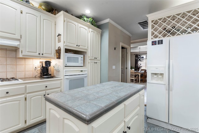 kitchen featuring white cabinetry, a kitchen island, tile counters, and white appliances