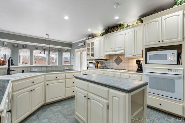 kitchen featuring sink, white appliances, hanging light fixtures, decorative backsplash, and tile countertops