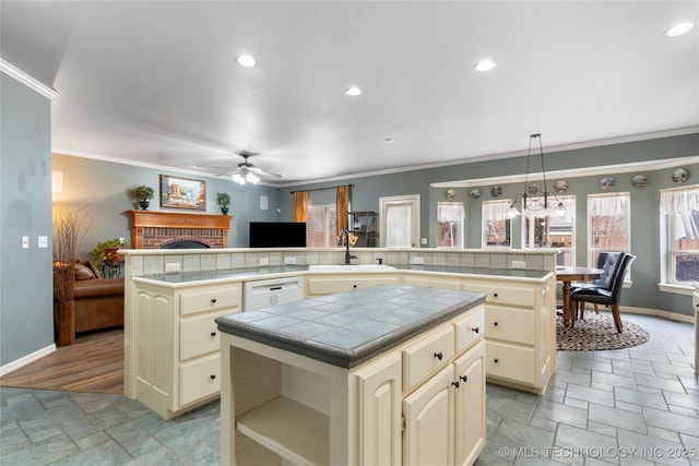 kitchen with hanging light fixtures, tile counters, sink, and a kitchen island