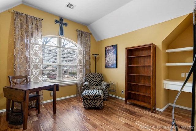 sitting room with hardwood / wood-style flooring and vaulted ceiling