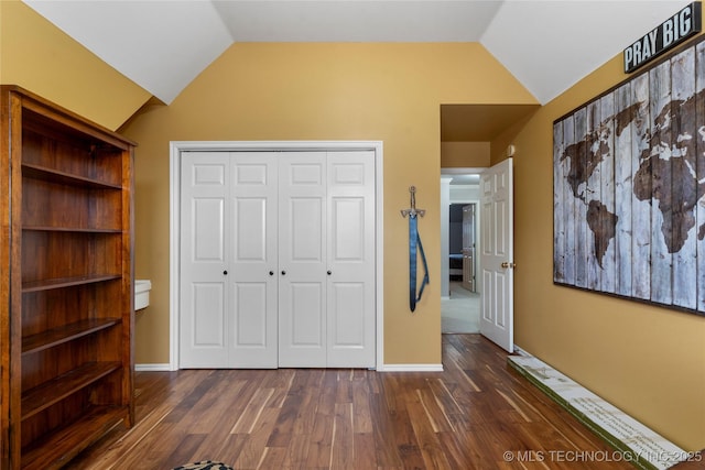 unfurnished bedroom with dark wood-type flooring, vaulted ceiling, and a closet