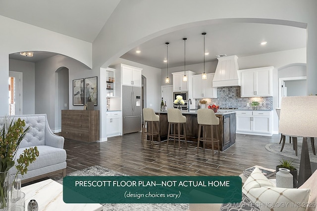 kitchen with hanging light fixtures, premium range hood, white cabinets, and a center island with sink