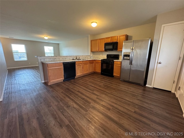 kitchen with sink, light stone counters, black appliances, dark hardwood / wood-style flooring, and kitchen peninsula