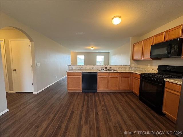 kitchen featuring dark wood-type flooring, kitchen peninsula, sink, and black appliances