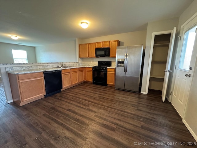 kitchen with light stone countertops, sink, dark wood-type flooring, and black appliances