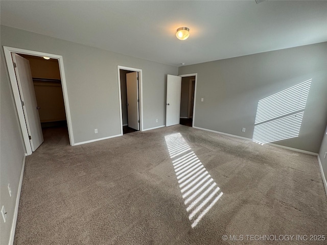 unfurnished bedroom with a walk in closet and carpet