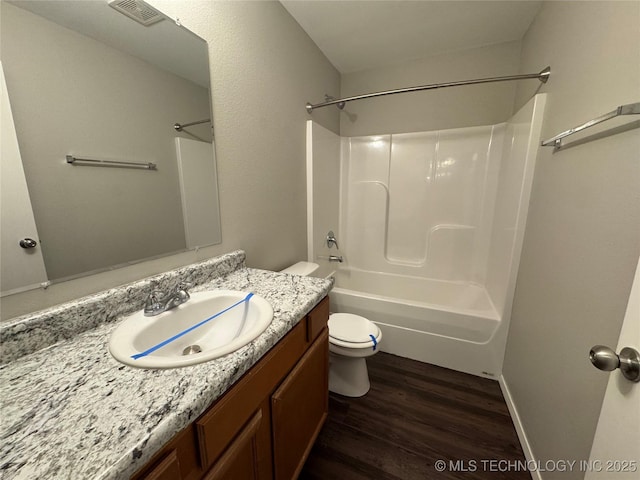 full bathroom with vanity, bathing tub / shower combination, hardwood / wood-style floors, and toilet