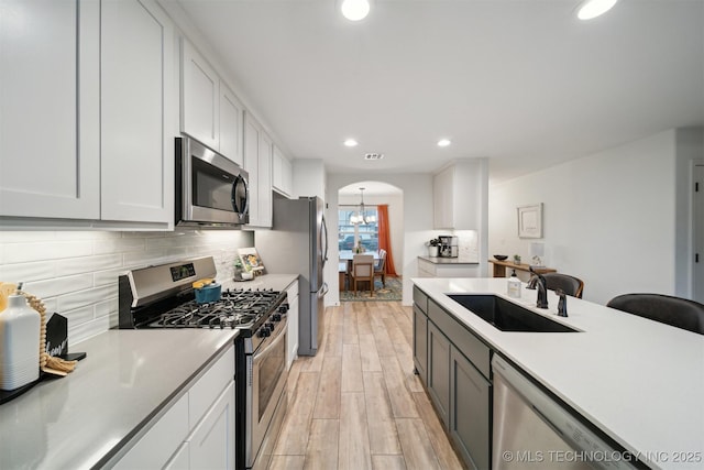 kitchen with sink, light hardwood / wood-style flooring, appliances with stainless steel finishes, white cabinetry, and tasteful backsplash