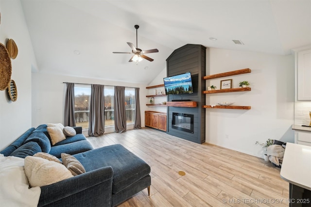 living room featuring ceiling fan, a large fireplace, high vaulted ceiling, and light wood-type flooring