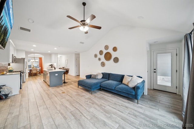 living room featuring vaulted ceiling, light hardwood / wood-style floors, and ceiling fan