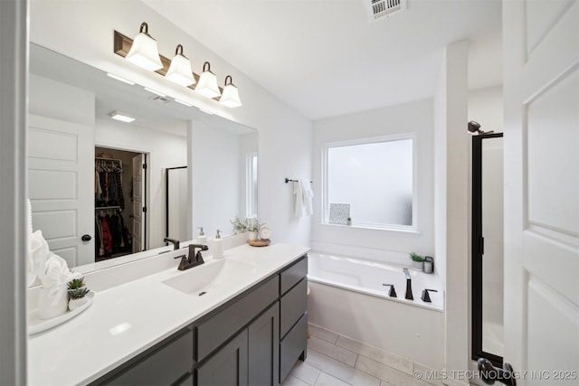 bathroom featuring vanity, a bath, and tile patterned flooring