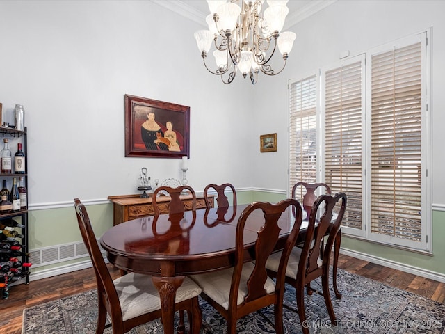 dining space with crown molding, visible vents, a chandelier, wood finished floors, and baseboards