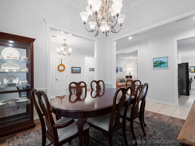 dining area featuring visible vents, baseboards, an inviting chandelier, ornamental molding, and light wood-style floors