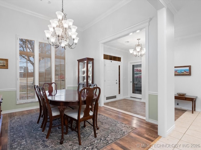dining area featuring wood finished floors, an inviting chandelier, baseboards, and ornamental molding