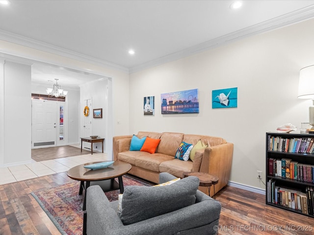 living area with hardwood / wood-style floors, an inviting chandelier, and ornamental molding