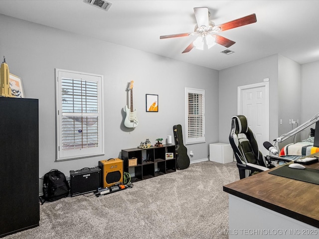 carpeted office with visible vents, baseboards, and a ceiling fan