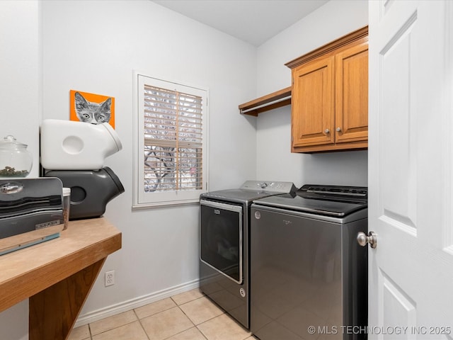 laundry room with baseboards, washer and clothes dryer, light tile patterned flooring, and cabinet space