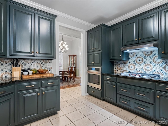 kitchen with light tile patterned floors, an inviting chandelier, ornamental molding, appliances with stainless steel finishes, and under cabinet range hood