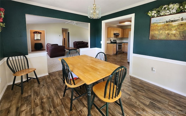 dining area with dark wood-type flooring, ornamental molding, and a chandelier