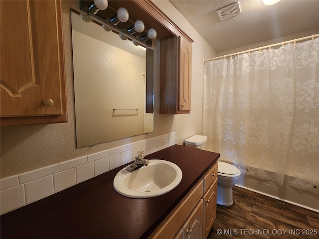 bathroom with wood-type flooring, vanity, a textured ceiling, and toilet