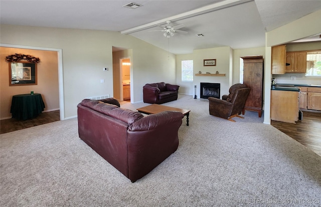 carpeted living room with vaulted ceiling with beams, sink, and ceiling fan