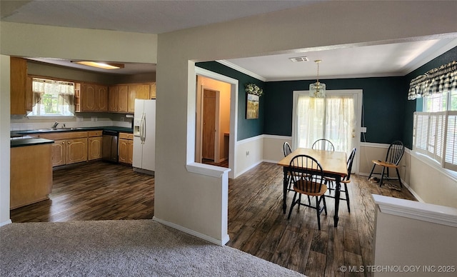 kitchen featuring sink, decorative light fixtures, stainless steel dishwasher, dark hardwood / wood-style floors, and white refrigerator with ice dispenser