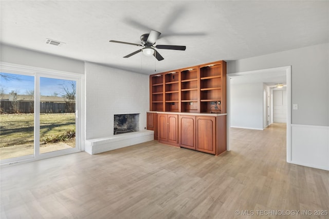 unfurnished living room with ceiling fan, a fireplace, and light hardwood / wood-style flooring