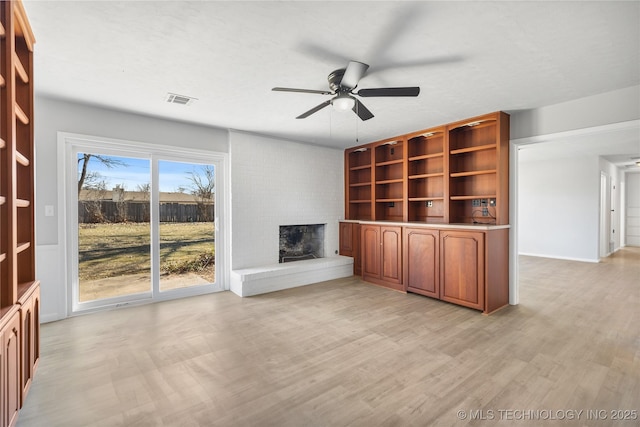 unfurnished living room with ceiling fan, a fireplace, and light hardwood / wood-style floors