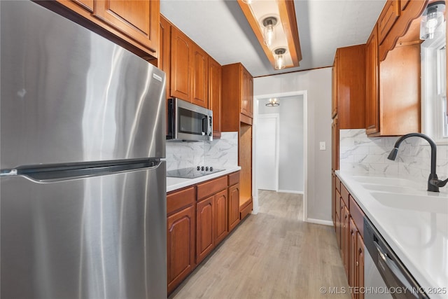 kitchen featuring tasteful backsplash, sink, stainless steel appliances, and light hardwood / wood-style floors