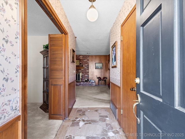 carpeted foyer featuring wooden walls, a fireplace, and a textured ceiling