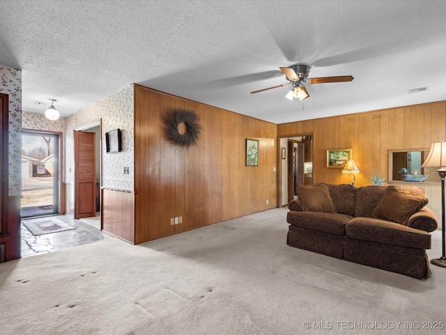 living room featuring ceiling fan, light carpet, and a textured ceiling