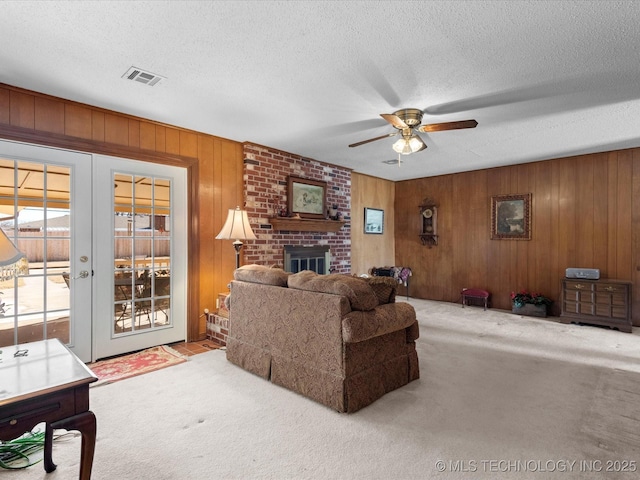 living room with ceiling fan, a fireplace, carpet floors, a textured ceiling, and french doors