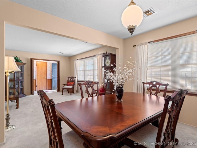 dining space with light carpet and a textured ceiling