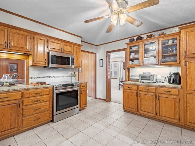 kitchen with light stone counters, appliances with stainless steel finishes, crown molding, and decorative backsplash