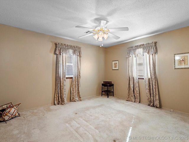 empty room with ceiling fan, a healthy amount of sunlight, and a textured ceiling