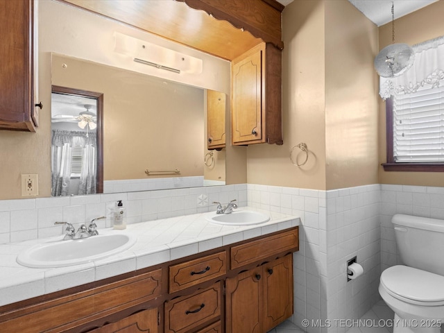 bathroom featuring vanity, tile walls, and toilet