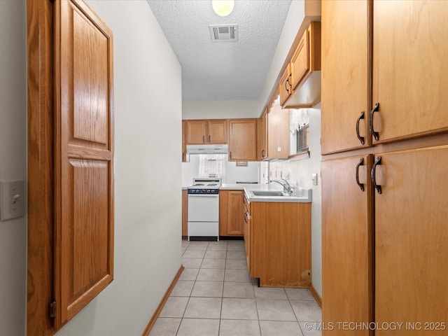 kitchen with electric stove, sink, light tile patterned floors, and a textured ceiling