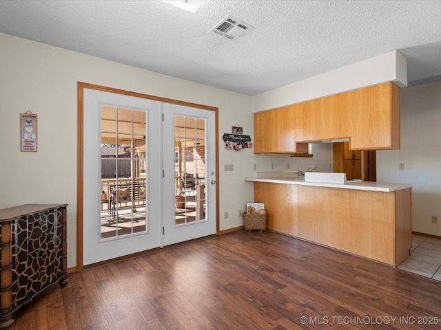 kitchen with dark wood-type flooring, kitchen peninsula, and a textured ceiling