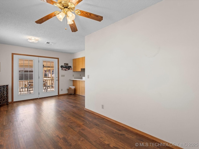 unfurnished living room with ceiling fan, dark wood-type flooring, and a textured ceiling