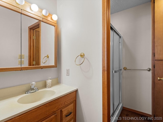 bathroom featuring vanity, a shower with door, and a textured ceiling