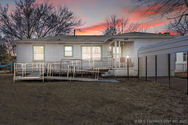 back house at dusk with a garage and a lawn