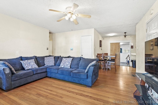 living room featuring hardwood / wood-style flooring, a textured ceiling, and ceiling fan