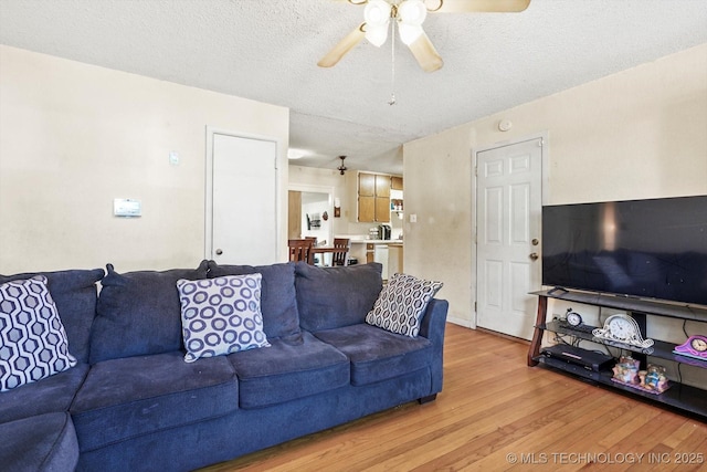 living room featuring a textured ceiling, light hardwood / wood-style floors, and ceiling fan