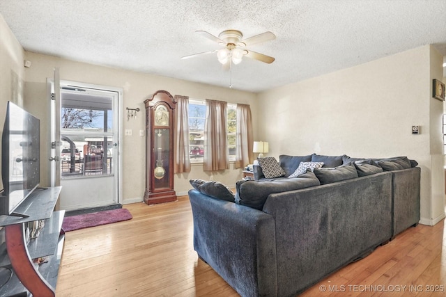 living room featuring ceiling fan, a textured ceiling, and light wood-type flooring