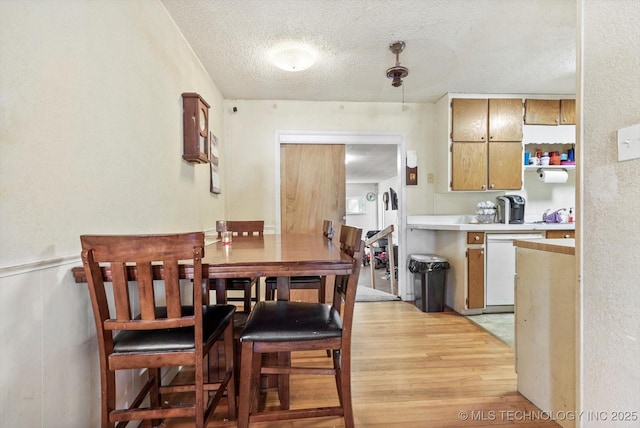 kitchen with a textured ceiling, light hardwood / wood-style flooring, and dishwasher