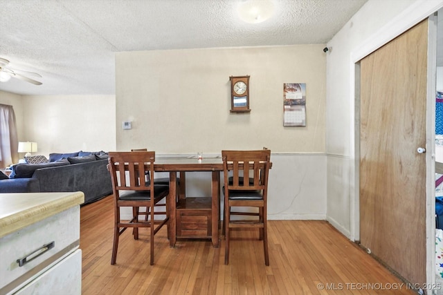 dining space featuring a textured ceiling, ceiling fan, and light wood-type flooring