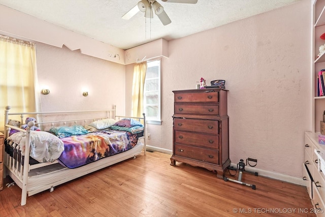 bedroom featuring multiple windows, ceiling fan, a textured ceiling, and light wood-type flooring