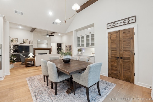2325 E 134th Cir, Bixby, OK 74008 - dining room with light wood-style floors, a ceiling fan, high vaulted ceiling, a fireplace, and a chandelier