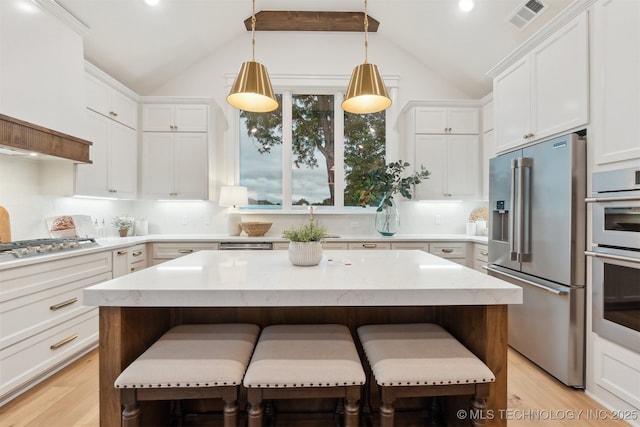 2325 E 134th Cir, Bixby, OK 74008 - kitchen with stainless steel appliances, lofted ceiling, light wood-type flooring, white cabinetry, and a kitchen bar